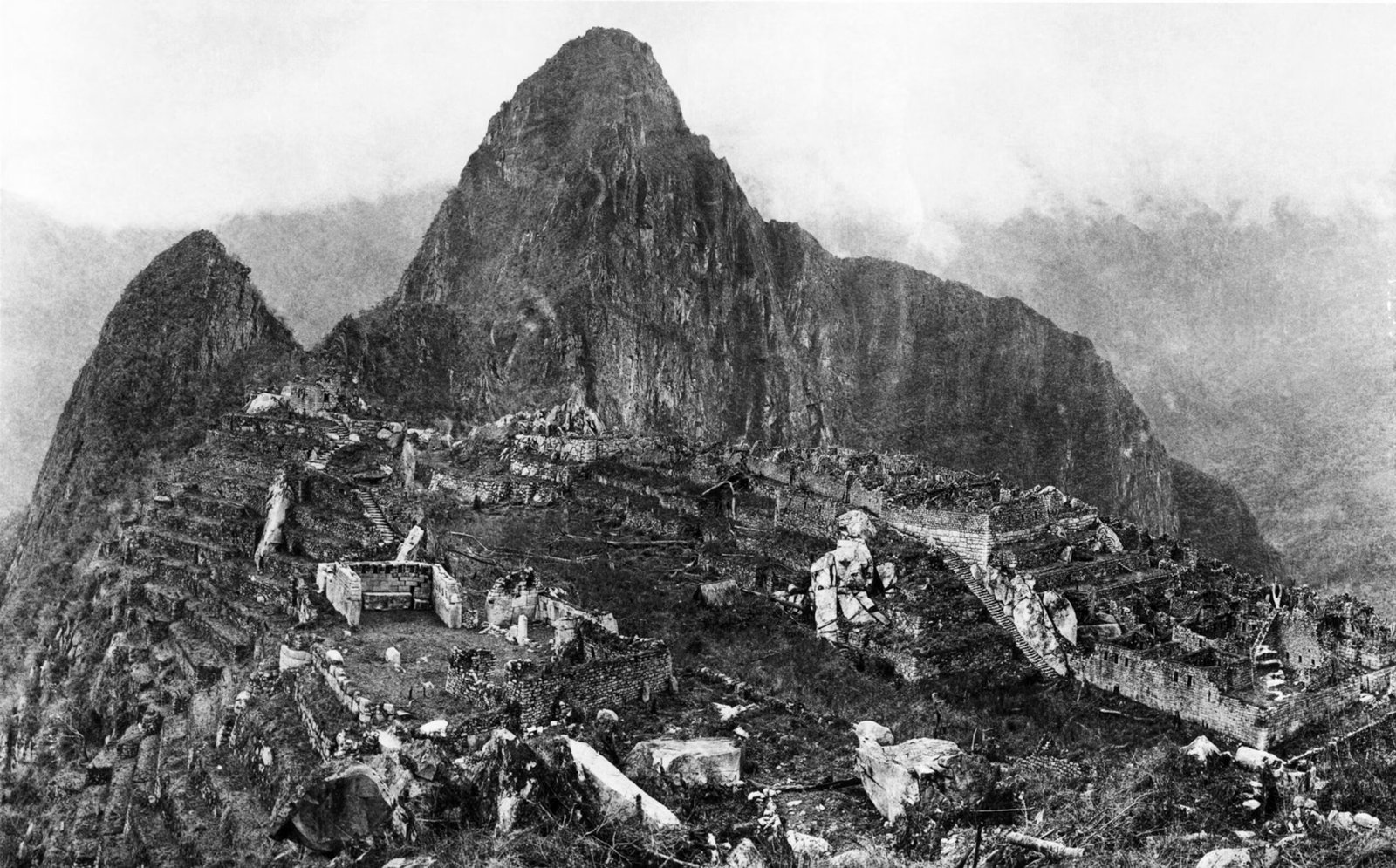 Black-and-white photo of Machu Picchu taken in 1912 by Hiram Bingham III, showing the cleared Inca ruins with terraces and stone structures.