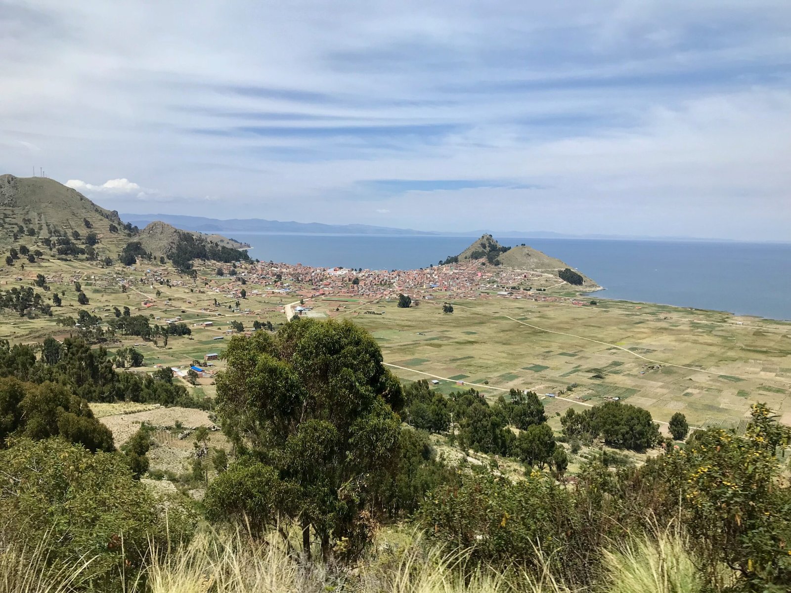 View of Copacabana, Bolivia, on the shores of Lake Titicaca, with farmland in the foreground and the lake stretching into the distance.