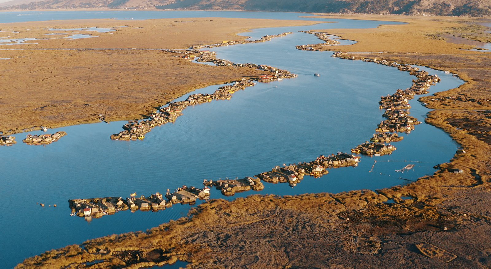 Aerial view of the Uros floating islands on Lake Titicaca, Peru, showing clusters of man-made reed islands surrounded by blue water. Photo credit: Tobias Deml.