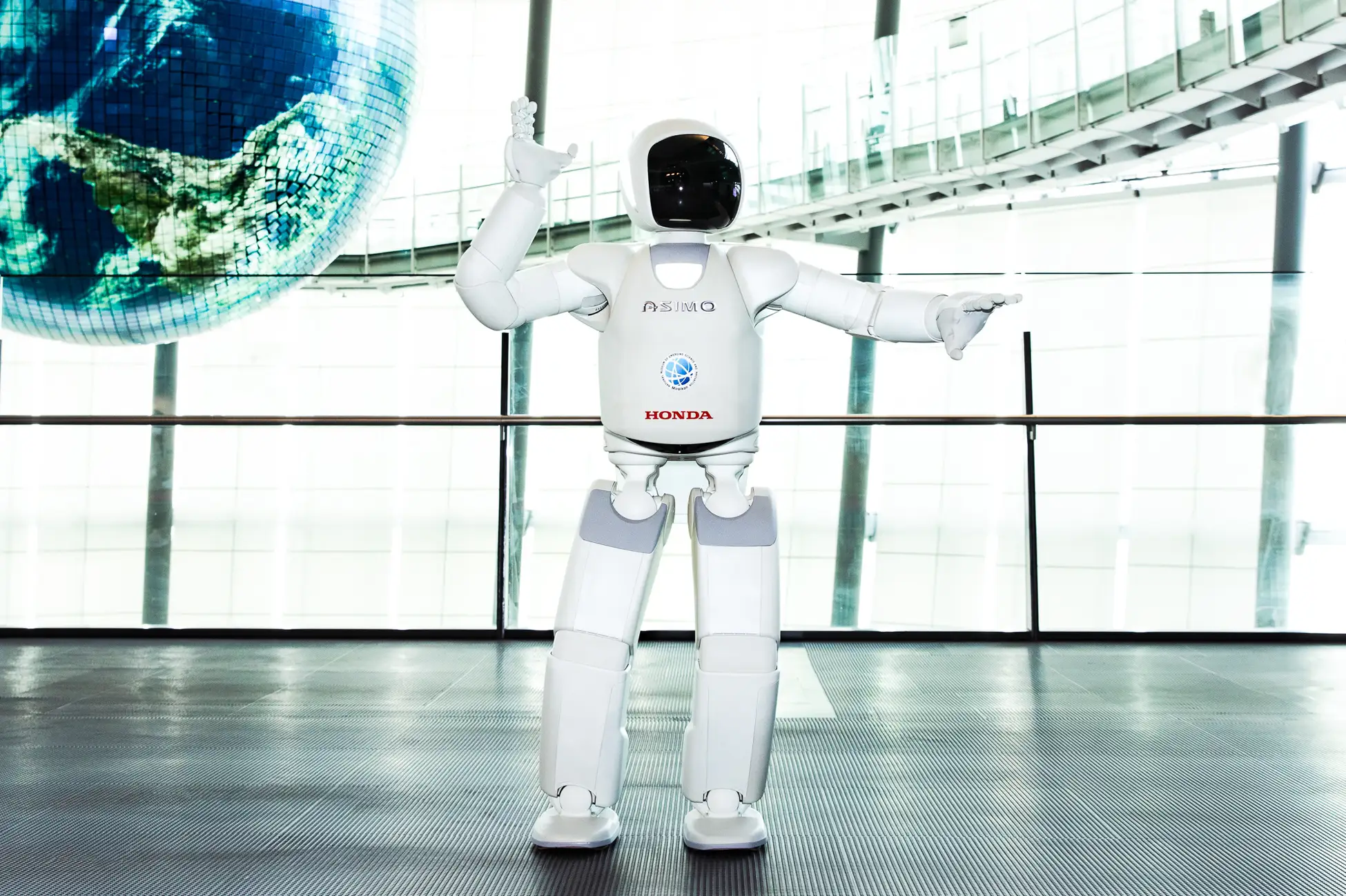 ASIMO the humanoid robot performing at Miraikan in Tokyo, with the Geo-Cosmos Earth display in the background