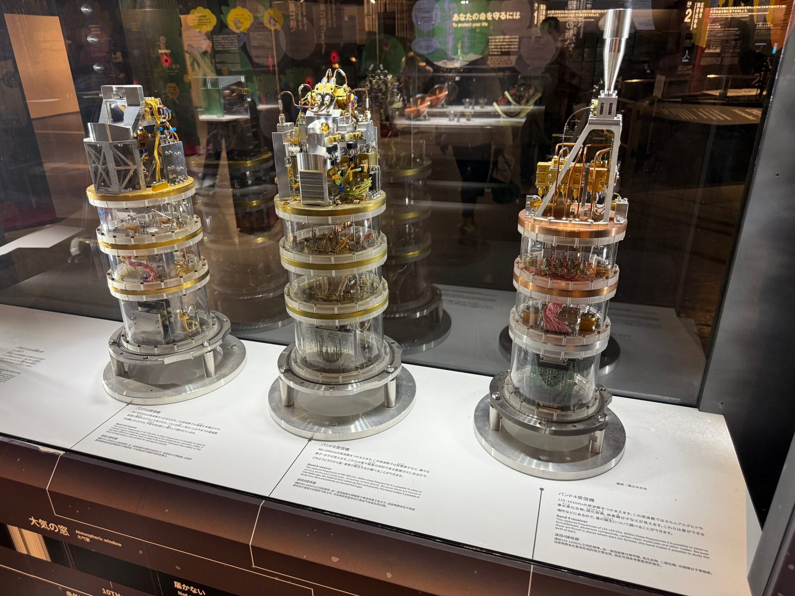 Radio astronomy receivers at Miraikan displayed in a glass case, featuring intricate multi-tiered instruments used to capture cosmic radio waves.