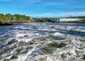 Turbulent whitewater rapids at the Reversing Falls in Saint John, New Brunswick, viewed at low tide with the Reversing Falls Bridge spanning the gorge in the background.