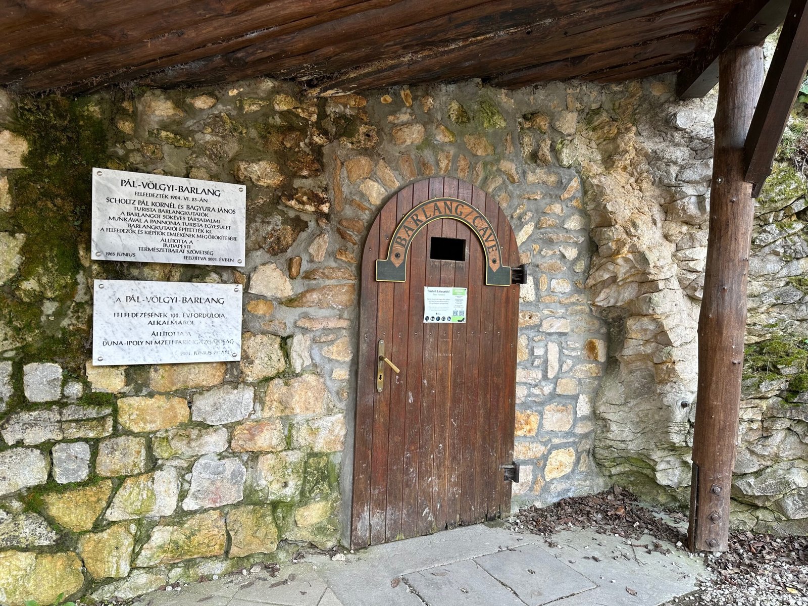 Wooden entrance door to Palvolgyi Cave in Budapest with a sign marking the cave’s official entry point