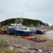 Fishing boats and kayaks rest on the exposed seafloor during a Bay of Fundy tide in St. Martins, New Brunswick, showcasing the region’s extreme tidal range.