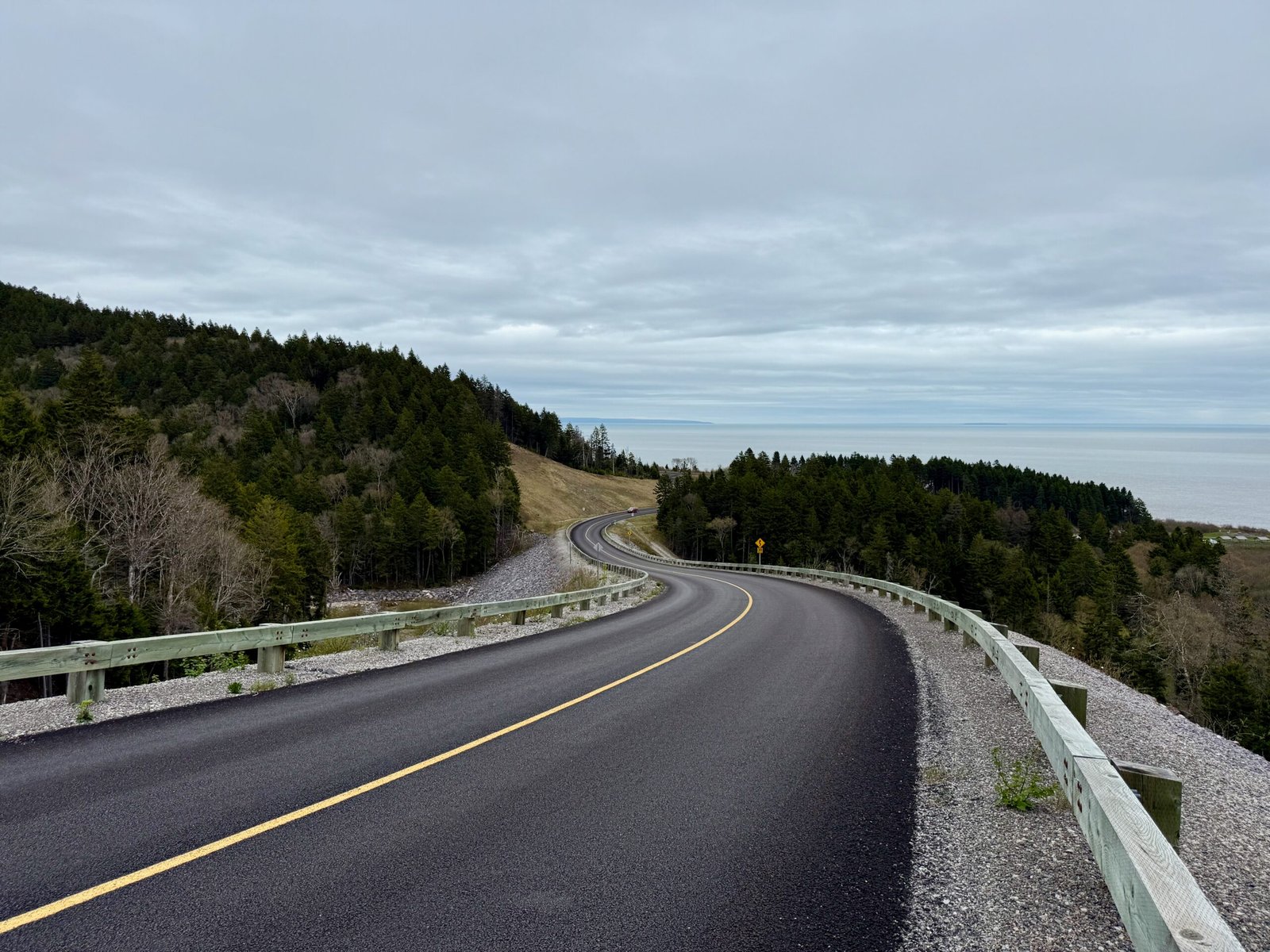 Winding Fundy Trail Parkway road with Bay of Fundy coastline in the distance