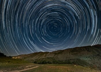 Circular star trails above a dark horizon, symbolizing the passage of time in places where time slows down.