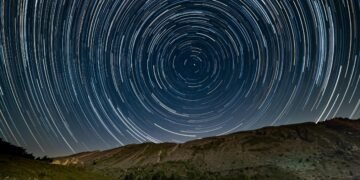 Circular star trails above a dark horizon, symbolizing the passage of time in places where time slows down.