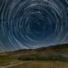 Circular star trails above a dark horizon, symbolizing the passage of time in places where time slows down.