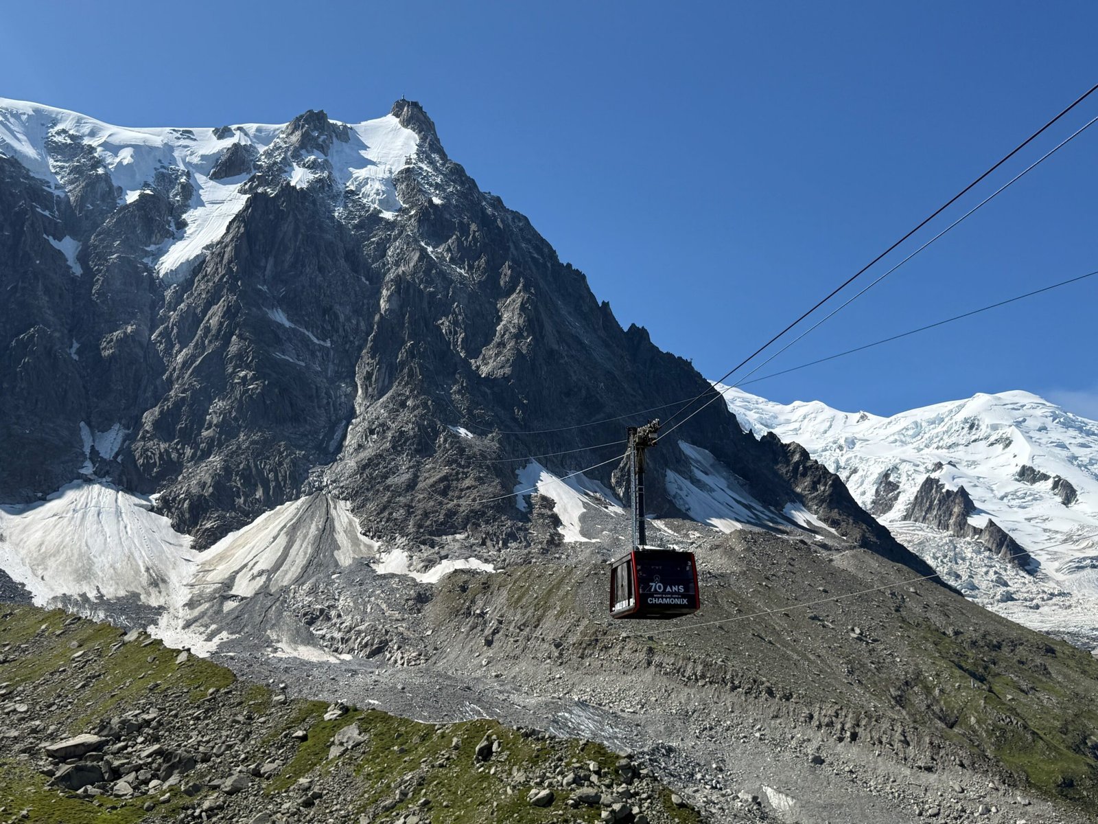Cable car descending from the Aiguille du Midi to the Plan de l’Aiguille mid-station, showing the steep drop and long unsupported span of the cables.