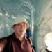 Don Trynor, author of Curious Don, inside the Grotte de Glace at Mer de Glace, surrounded by smooth blue glacier ice.