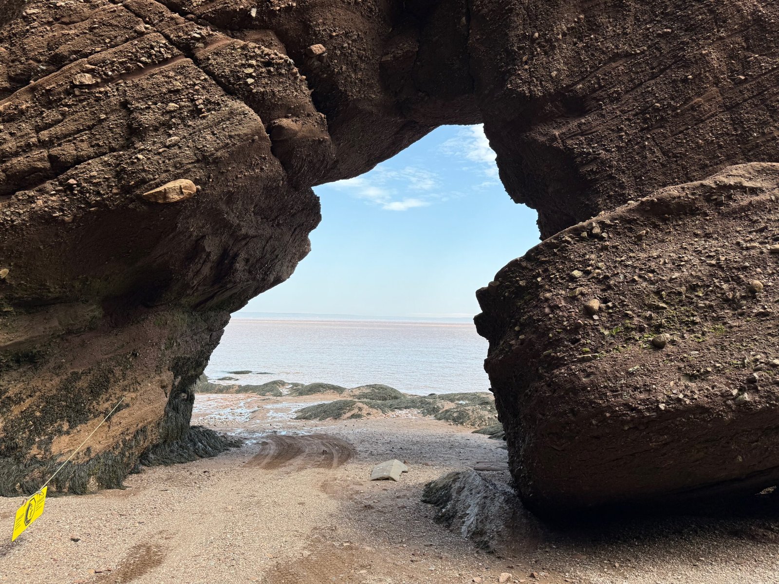 Rock arch of conglomerate stone on the beach south of Hopewell Rocks, shaped by the Hopewell Rocks tides, with the Bay of Fundy and Nova Scotia on the horizon.