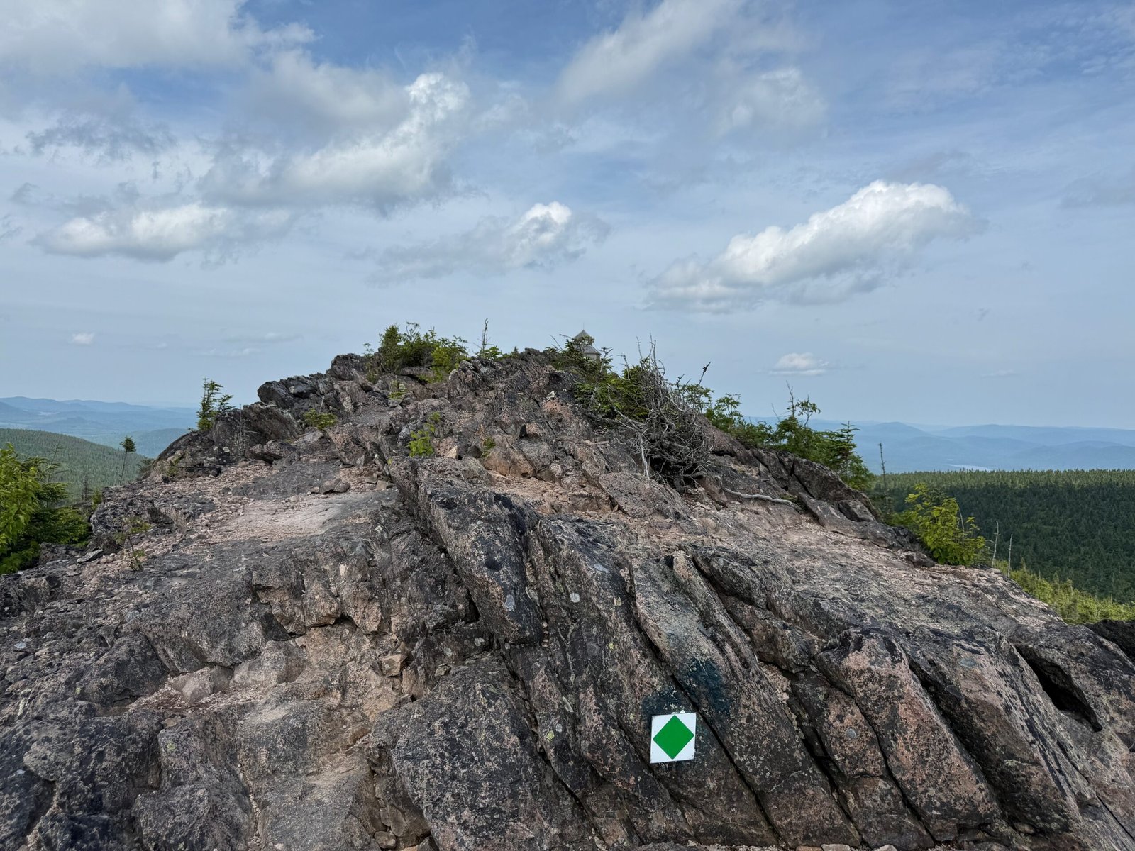 Rhyolite rock formation at the summit of Mount Carleton with a green trail marker in Mount Carleton Provincial Park, New Brunswick.