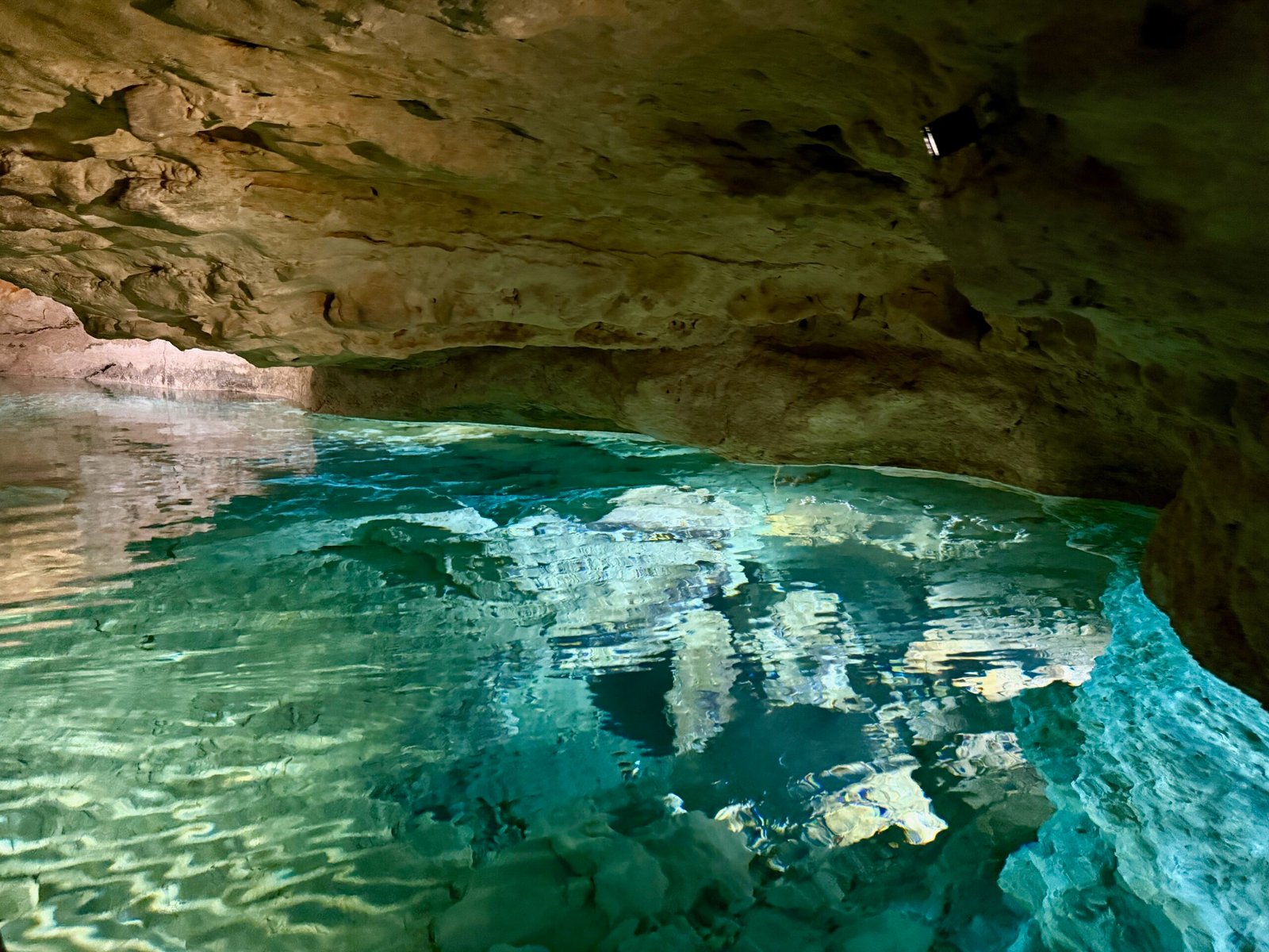 Bluish water flowing through a low-ceiling passage of Tapolca Lake Cave, part of the underground karst river.