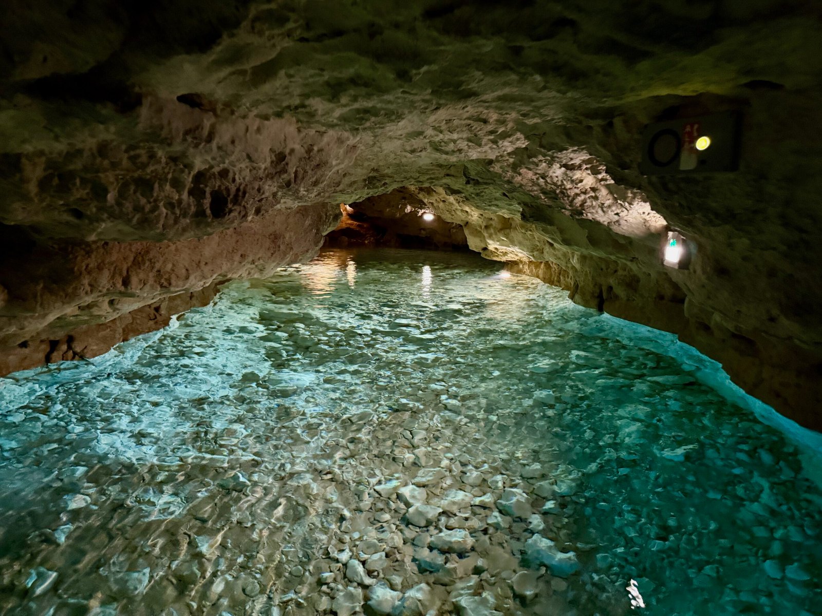 Blue spring water flowing through Tapolca Lake Cave with a very low ceiling section of the underground passage.