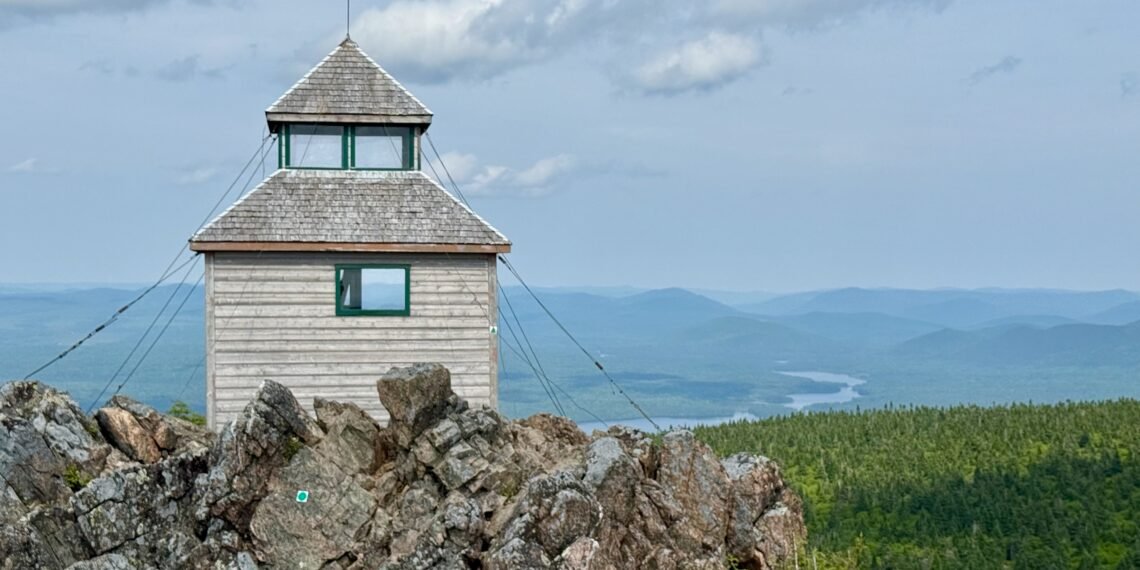 Wooden fire tower at the summit of Mount Carleton with Nictau Lake and Appalachian Mountains in the distance, Mount Carleton Provincial Park, New Brunswick.