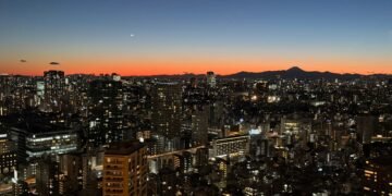 Tokyo Tower sunset view of the city skyline with Mount Fuji silhouetted on the horizon, seen from the main observation deck.